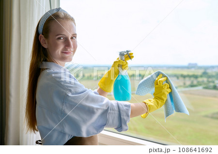 Young woman cleaning windows using spray and rag 108641692
