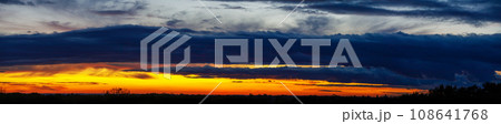 Panoramic sunset sky with heavy dark blue clouds and orange line of sun Panoramic sunset sky with heavy dark blue clouds and orange line of sun 108641768
