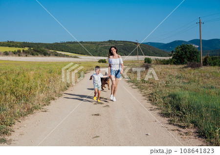 Mother and son walking in nature on the road of a rural field 108641823