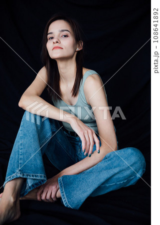 Woman in jeans posing on black background 108641892