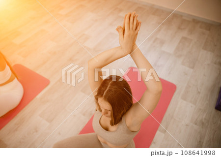 Girl does yoga. Young woman practices asanas on a beige one-ton background. Girl does yoga. Young woman practices asanas on a beige one-ton background. 108641998
