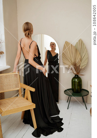 Woman in black dress on white background in the studio. Elegant lady in long gown. Sexy girl in formal prom dress. 108642005