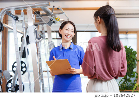 スポーツジムの入会案内をするスタッフと客 108642927