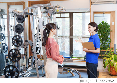 スポーツジムの入会案内をするスタッフと客 108642932