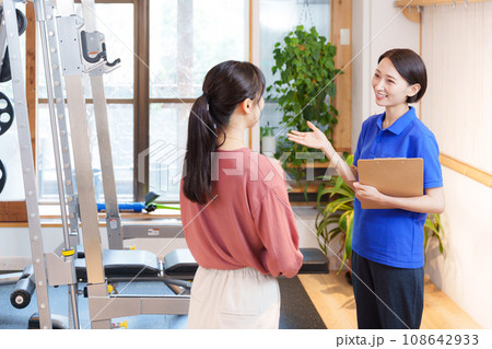 スポーツジムの入会案内をするスタッフと客 108642933