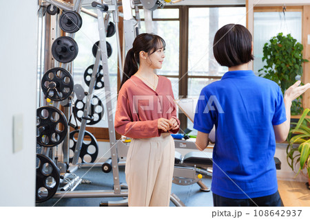 スポーツジムの入会案内をするスタッフと客 108642937