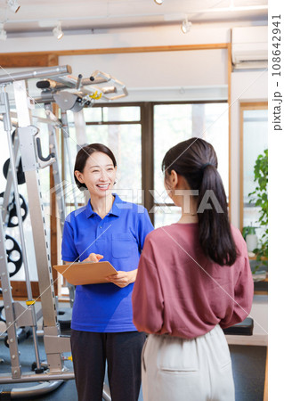 スポーツジムの入会案内をするスタッフと客 108642941