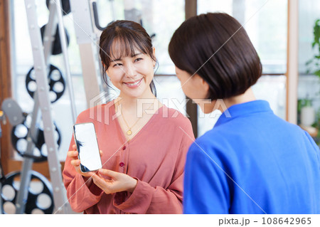 スポーツジムのスタッフにスマホ画面を見せる客 スポーツジムのスタッフにスマホ画面を見せる客 108642965