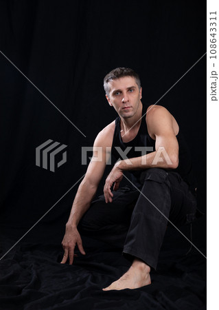 a man in dark clothes sits in a dark room 108643311