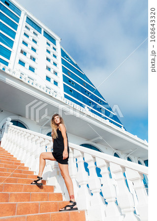 a woman stands on the stairs near a tall building 108643320