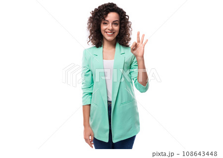 young stylish slim caucasian female model with curly shoulder-length black hair is dressed in a blue young stylish slim caucasian female model with curly shoulder-length black hair is dressed in a blue 108643448