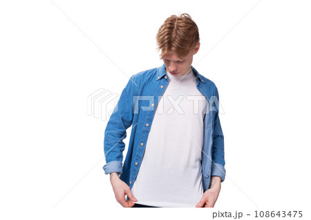 young red-haired guy in a blue shirt and white t-shirt shows a mockup for advertising young red-haired guy in a blue shirt and white t-shirt shows a mockup for advertising 108643475