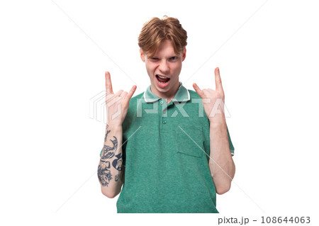 young emotional caucasian man with red hair dressed in a green t-shirt shows his coolness against 108644063