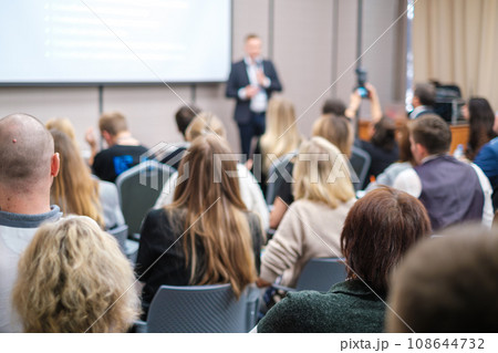 Back view of businesswoman attending presentation with diverse participants in conference hall  108644732