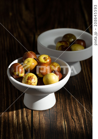 Sunlight shining on green dates on a wooden table board. 108645593