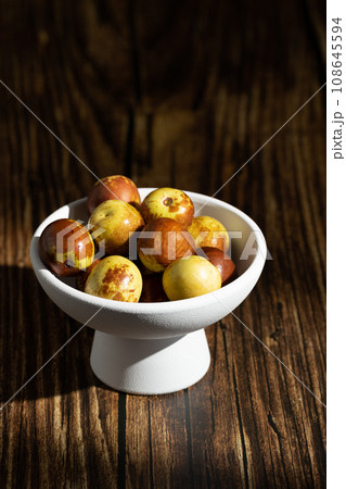 Sunlight shining on green dates on a wooden table board. 108645594