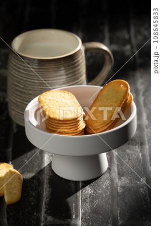 Sunlight shining on a slate board with a cup of milk and cookies. Sunlight shining on a slate board with a cup of milk and cookies. 108645833