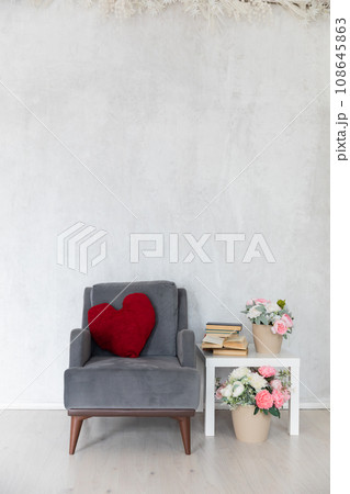 grey armchair with cushion with coffee table with books and flowers 108645863