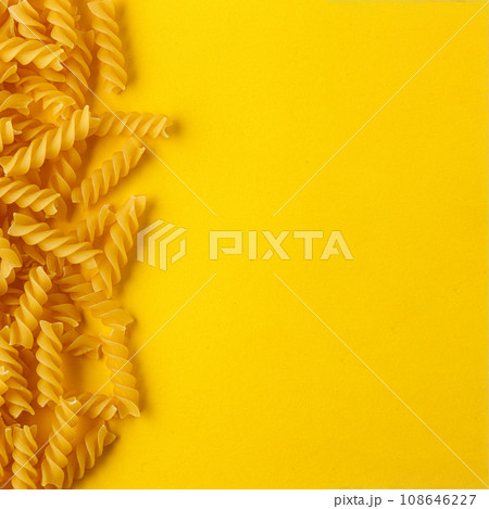 Different types and shapes of dry italian pasta on a yellow background 108646227