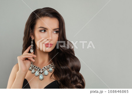 Cheerful young brunette model woman with long wavy hairdo, diamond jewelry earring and necklace  108646865