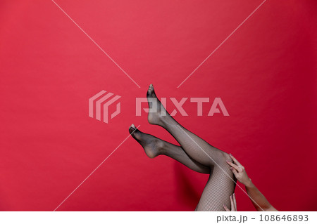 slender beautiful women's legs on a red background 108646893