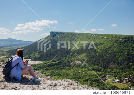 a woman sitting with a phone on a mountain hiking journey nature a woman sitting with a phone on a mountain hiking journey nature 108646971