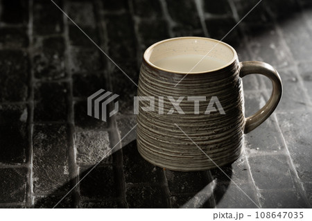 Sunlight shining on a slate board with a cup of milk. Sunlight shining on a slate board with a cup of milk. 108647035