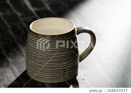 Sunlight shining on a slate board with a cup of milk. 108647037