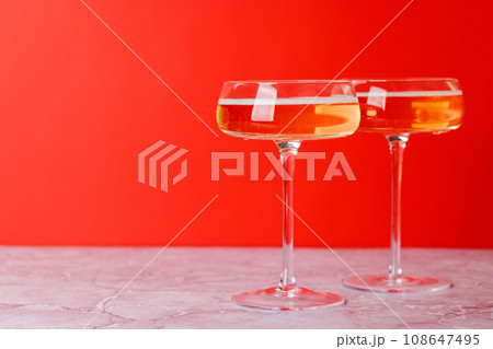 Two champagne glasses on a red Two champagne glasses on a red 108647495
