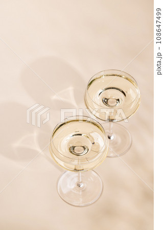 Two champagne glasses on a beige 108647499