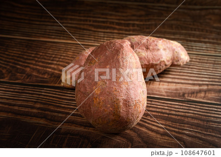 Old sweet potatoes placed on a wooden board. Old sweet potatoes placed on a wooden board. 108647601