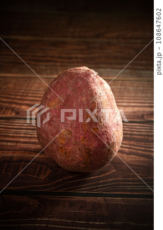 Old sweet potatoes placed on a wooden board. 108647602