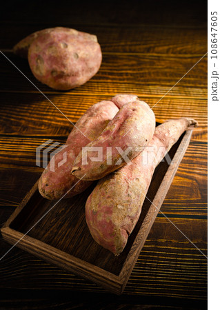 Old sweet potatoes placed on a wooden board. 108647605