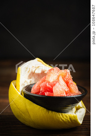 Grapefruits with red flesh placed on a wooden board in a bowl. Grapefruits with red flesh placed on a wooden board in a bowl. 108647687