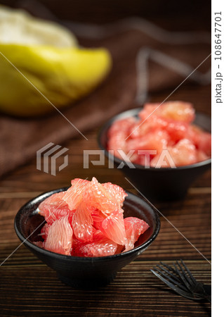 Grapefruits with red flesh placed on a wooden board in a bowl. Grapefruits with red flesh placed on a wooden board in a bowl. 108647701