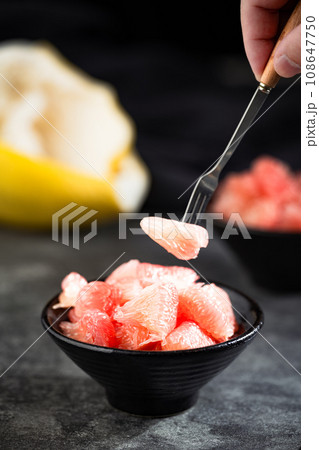 Sunlight shining on grapefruits with red flesh placed on a slate board in a bowl. 108647750