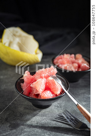 Sunlight shining on grapefruits with red flesh placed on a slate board in a bowl. 108647755