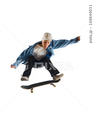 Teen boy, active guy in casual clothes in motion, training, practicing stunts on skateboard isolated over white background 108649031