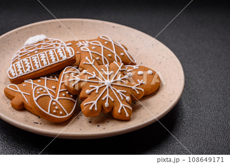 Beautiful Christmas gingerbread cookies of different colors on a ceramic plate Beautiful Christmas gingerbread cookies of different colors on a ceramic plate 108649171