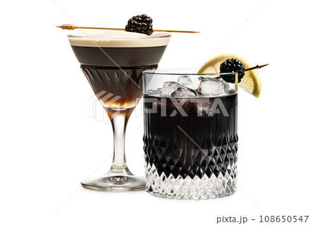 Set of Black Russian cocktails in crystal-clear glass sits against a white background 108650547