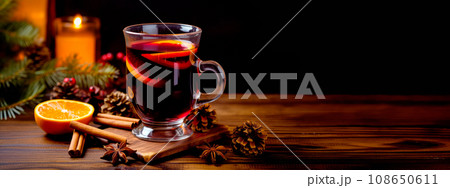 Christmas red mulled wine in a cup with cinnamon sticks, orange slices and winter decorations on wooden background 108650611