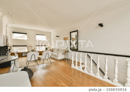 a living room with white walls and hardwood flooring, including a staircase leading up to the upper landing area a living room with white walls and hardwood flooring, including a staircase leading up to the upper landing area 108650916
