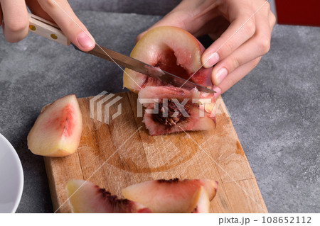 Authentic female hands cutting a fresh ripe peach on wooden cutting board, food lifestyle 108652112