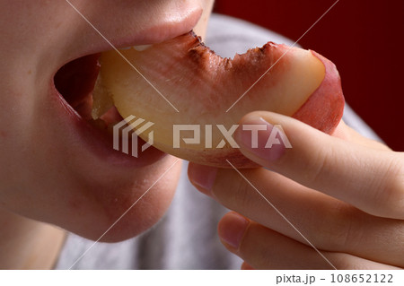 female hand putting a piece of ripe peach in the mouth, healthy food dessert female hand putting a piece of ripe peach in the mouth, healthy food dessert 108652122