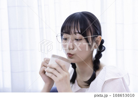 日差しがさしこむ部屋でコーヒーを飲む若い女性 日差しがさしこむ部屋でコーヒーを飲む若い女性 108653010