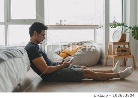 Lonely asian man using smartphone for social media alone in his apartment 108653904