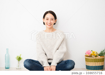 壁にもたれかかって座る若い女性　ライフスタイルイメージ 108655716