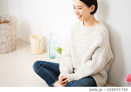 壁にもたれかかって座る若い女性　ライフスタイルイメージ 108655740