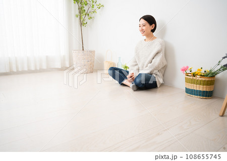 壁にもたれかかって座る若い女性　ライフスタイルイメージ 108655745