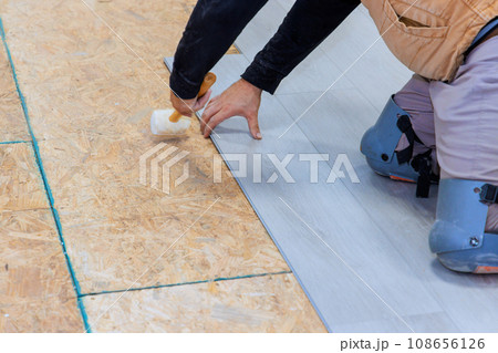 An installation worker installs vinyl laminate flooring in new home 108656126